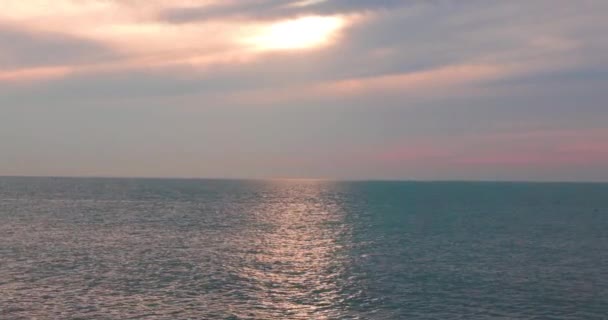 这段宁静的镜头捕捉了柔和落日的余晖下大海的宁静美丽 在一定程度上被云彩遮掩着 反射着温暖的光芒 反射着平静的海浪 — 图库视频影像