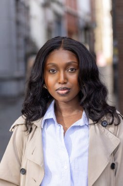 Bu resim hareketli bir şehir caddesinde duran genç siyahi bir kadının huzurlu bir portresini sunuyor. Kameraya bakarken, bakışları doğrudan ve durağan, içsel bir bakış ile. Doğal hali.