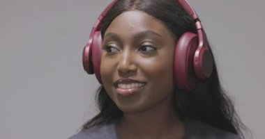 Bu çekici klip, pembe kulaklık takan neşeli bir Afrikalı Amerikalı kadını gösteriyor. Hoş bir işitsel deneyime dalmış gibi görünüyor, muhtemelen en sevdiği müziği dinliyor. Gülüşü ve...