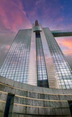 The grandeur of an Art Deco skyscraper is magnified against the canvas of a dramatic sunset sky. The buildings reflective glass captures the fading light, while architectural details stand clipart