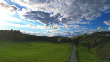 Bu çarpıcı hava görüntüsü Belçika 'nın Ardennes bölgesindeki Hautes Fagnes' in geniş güzelliğini yansıtıyor. Klipte, çarpıcı bir gökyüzü altında dar bir yola bölünmüş canlı yeşil alanlar yer alıyor.