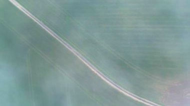 Bu drone videosu, yüzen sis bulutlarıyla örtülü yemyeşil ekin tarlalarının büyüleyici görüntüsünü yakalıyor. Kırsal yolların dingin desenleri, ruhani sisle birleştiğinde,