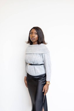 Zarafet ve özgüven saçan şık bir kadın, modern modayı canlı beyaz bir zemine karşı sergiliyor.