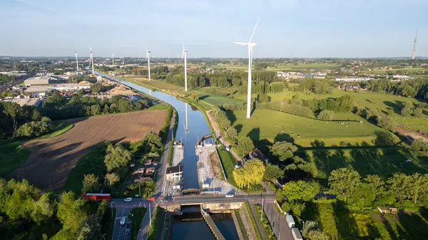 stock image Sluis van Lot, kanaal Brussel, Charleroi, Lot, Beersel, 18th of May, 2024 This aerial image showcases a scenic canal lined with tall wind turbines and lush green fields on either side. The canal winds