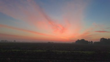 Sabahın erken saatlerinde canlı renkler ile gökyüzünü ağaçların ve çalıların siluetleriyle doldurur.