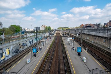 Halle, Belçika, 15 Mayıs, 2024 tren istasyonunun arka planında birden fazla ray ve mavi bir gökyüzü var.