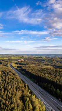 Bu dikey hava fotoğrafı Belçika Emmels yakınlarındaki Hautes Fagnes bölgesindeki sık ormanlardan geçen E42 otoyolunu yakalar. Karayolu, iyi korunmuş şeritleriyle, keskin bir şekilde zıtlaşıyor