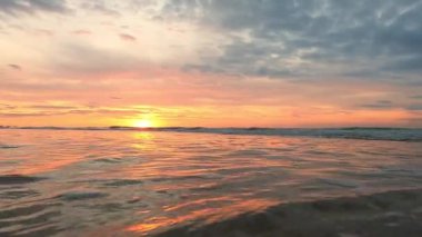 Okyanusun üzerinde güzel bir gün batımı, rahatlatıcı dalgalar, çarpıcı sahili görüntülemek için mükemmel.