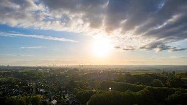 Bulutlu gökyüzü ve yemyeşil manzaralı huzurlu kırsal bölgede nefes kesici bir günbatımı manzarasının tadını çıkar.