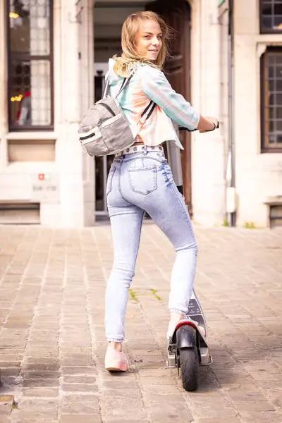 stock image A young woman rides an electric scooter happily in the city, living an ecofriendly lifestyle in the summer