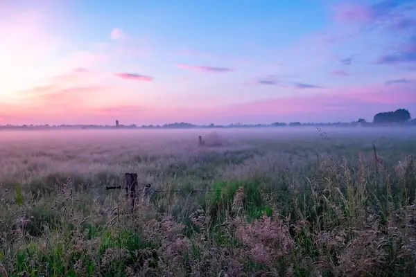 stock image Experiencing a tranquil sunrise over a foggy field reveals a serene and calm atmosphere against a vibrant sky