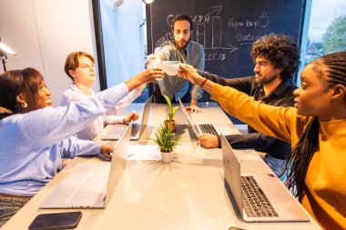 Modern ofis ortamındaki bir toplantıda çeşitli iş adamları kutlama ve kadeh kaldırıyor.