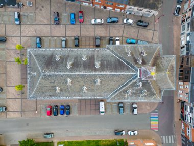 Simetrik tasarımı ve park halindeki arabaları şehir merkezinde havadan gören bir mimari yapı.