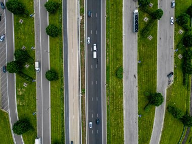 Çevresi yeşilliklerle çevrili, canlı bir kentsel ekosistem ve akan bir trafik gösteren modern bir otoyolun havadan görünüşü