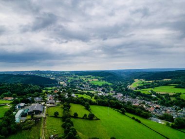 Stavelot, Liege, Belçika, 30 Haziran 2024, güzel bir kırsal günde yeşil tepeleri, köyleri ve bulutlu gökyüzünü gösteren büyüleyici bir hava manzarası.