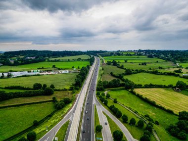 E42, A27 otoyolu Liege Trier, Stavelot, Liege, Belçika, 30 Haziran 2024, otoban dramatik bulutlar altında yeşil kırsal kesim, manzaralı tarım arazileri ve yollar.