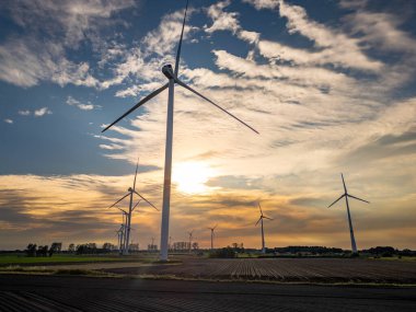 Bir alandaki rüzgar türbinlerinin manzaralı görüntüsü günbatımında yenilenebilir enerji ve çevresel sürdürülebilirliği somutlaştırır