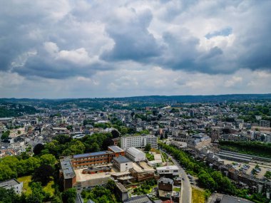 Verviers, Liege, Belçika, 30 Haziran 2024, büyüleyici bir kuş bakışı bulutlu gökyüzünün altındaki hareketli şehir manzarası, yemyeşil ve binalar