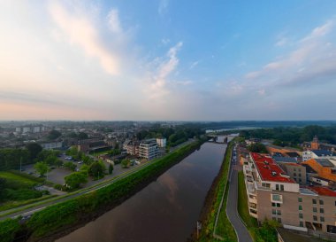 Duffel, Antwerp, Belçika, 25 Haziran 2024, Şafakta nehir, modern binalar ve yeşil çevreyle birlikte sakin şehir manzarası,