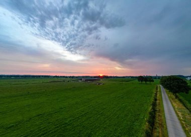 Göz kamaştırıcı bir günbatımı canlı ve ışıl ışıl renkler sergiliyor cennet bahçeleri ve sakin dolambaçlı bir yol