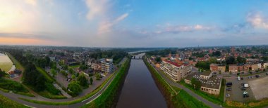 Duffel, Antwerp, Belçika, 25 Haziran 2024 'te şehir güzelliği gün batımında panoramik hava manzarasından görülebilen bir nehir tarafından vurgulandı.