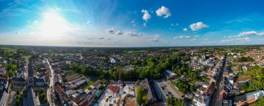 Arendonk, Antwerp, Belçika, 6 Ağustos 2024, sersemletici hava görüntüsü açık mavi gökyüzünün altında canlı bir yerleşim alanı sergiliyor.