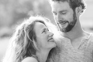 Siyah beyaz bir portre, birbirine sevgiyle bakan neşeli bir çifti yakın bir kucaklaşmada yakalar..