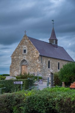 Dramatik bir gökyüzünün altındaki taş kilise, doğal güzellikle tarihi ve mimari cazibe sergiliyor.