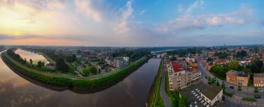 Duffel, Antwerp, Belçika, 25 Haziran 2024, günbatımında manzaralı bir şehir manzarası, renkli gökyüzü olan bir kanal boyunca evler sergileniyor çarpıcı bir manzara yaratıyor.