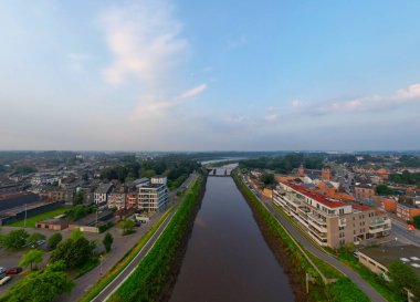 Duffel, Antwerp, Belçika, 25 Haziran 2024, bir şehirde yerleşim binaları ve yeşilliklerle çevrili bir kanal görüntüsü..