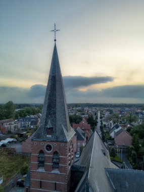 Rijkevorsel, Antwerp, Belçika, 7 Ağustos 2024, Saint Joseph Kilisesi, Bu, çarpıcı dramatik bir günbatımı gökyüzüne karşı güzel bir kilise çan kulesini gösteren havadan bir manzara.