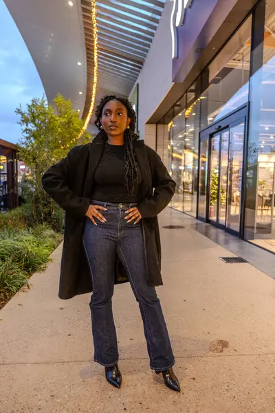 stock image A trendy, fashionable woman is standing confidently outside a modern and stylish retail space, exuding confidence