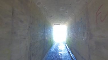 Uzun, karanlık bir tünel aniden parlak ışığa açılıyor ve duvarları süsleyen canlı graffiti sanatını ortaya çıkarıyor.