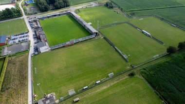 Rijkevorsel, Antwerp, Belçika, 1 Eylül 2024, yemyeşil alanlar arasında yuva yapmış canlı bir toplum spor sahasını güzel bir şekilde gösteren nefes kesici bir hava görüntüsü.