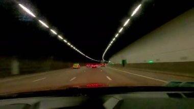 Parlak farlar ve hareketli trafik ışıklarıyla dolu uzun bir tünelde gece boyunca canlandırıcı bir sürüş.