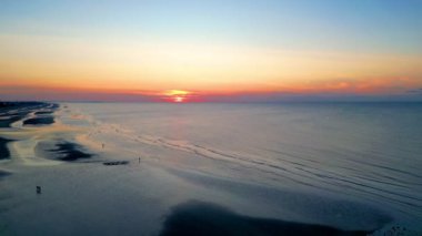 Şok edici bir günbatımı, sakin denizin üzerinde sıcak bir parıltı sağlar. Rahatlamak isteyen doğa aşıkları için mükemmeldir.