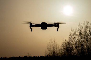 Güzel bir günbatımına karşı süzülen bir dron modern teknoloji ve doğanın karışımını sergiliyor.