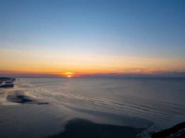Nefes kesici bir günbatımı, sakin okyanus dalgalarını ve güzel kumsalın sakin kıyılarını aydınlatıyor.