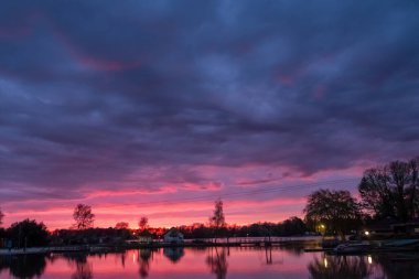 Nefes kesici ve büyüleyici bir gün batımı dingin ve huzurlu bir göl manzarasına canlı ve büyüleyici renkler saçar.