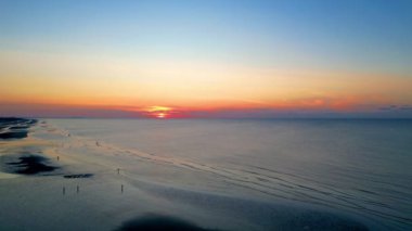 Nefes kesici bir günbatımı, dingin bir okyanusun üzerine canlı renkler saçar. Gerçekten hayranlık ve hayranlık uyandırır.