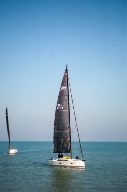 Nieuwpoort, Belçika, 5 Ekim 2024, güneşli bir günde sakin sularda yüzen iki yelkenli, yelkenciliğin özünü yakalıyor.