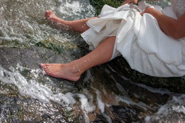 Çıplak ayakla dingin bir gelin, akarsu kenarında güzel bir gelinlik giymiş bir anın tadını çıkarıyor..