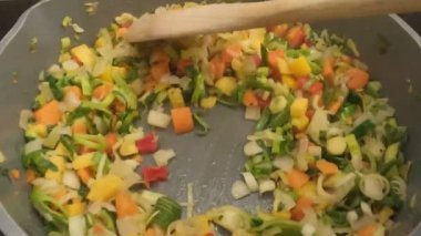 Sağlıklı bir yemek için tahta kaşıkla sotelenen canlı sebze karışımı.