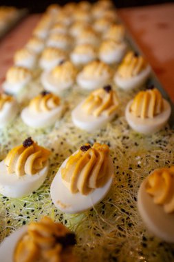 Canlı sarı dolgu ve taze otlarla süslenmiş baharatlı yumurtalardan oluşan görsel bir düzenleme.