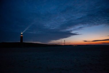 De Cocksdorp, Texel, Hollanda, 27 Ekim 2024, güzel ve çarpıcı bir deniz feneri alacakaranlıkta ışıl ışıl parlıyor, sakin kıyı manzarasına yumuşak bir ışık saçıyor.