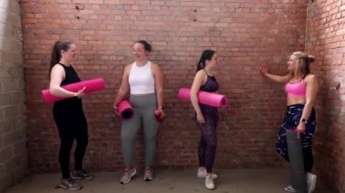 Canlı ve enerjik bir arkadaş grubu yoga minderleri ve ağırlık kaldırarak eğlenceli bir fitness seansının tadını çıkarmak için bir araya geldi.