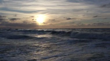 Gün batımındaki engin okyanusun nefes kesici ve çarpıcı manzarası, nazik dalgalar ve güzel boyanmış gökyüzü.