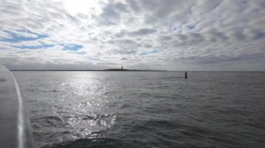 Güzel, sakin bir deniz manzarası sakin mavi sular ve geniş, yumuşak bulutlu bir gökyüzü sergiler.