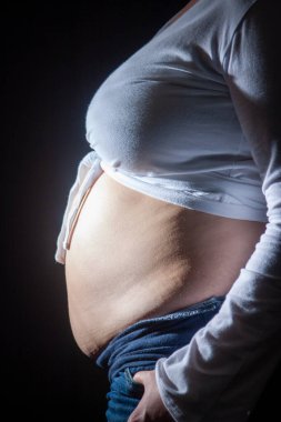 Göz alıcı hamile bir kadının güzel bir profil çekimi. Bebek çarpmasını kucaklıyor. Güzel, doğal bir ışıkla.