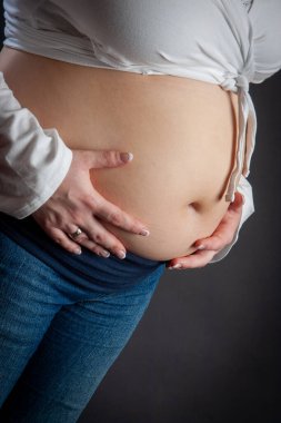 Güzel, hamile bir anne hamileliğin inanılmaz güzelliğini göstermek için nazikçe karnını şişiriyor.